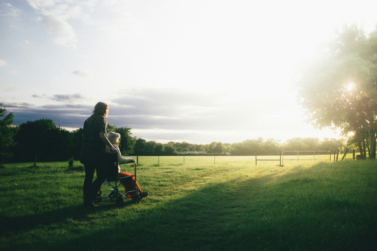 A carer supporting an older person outdoors